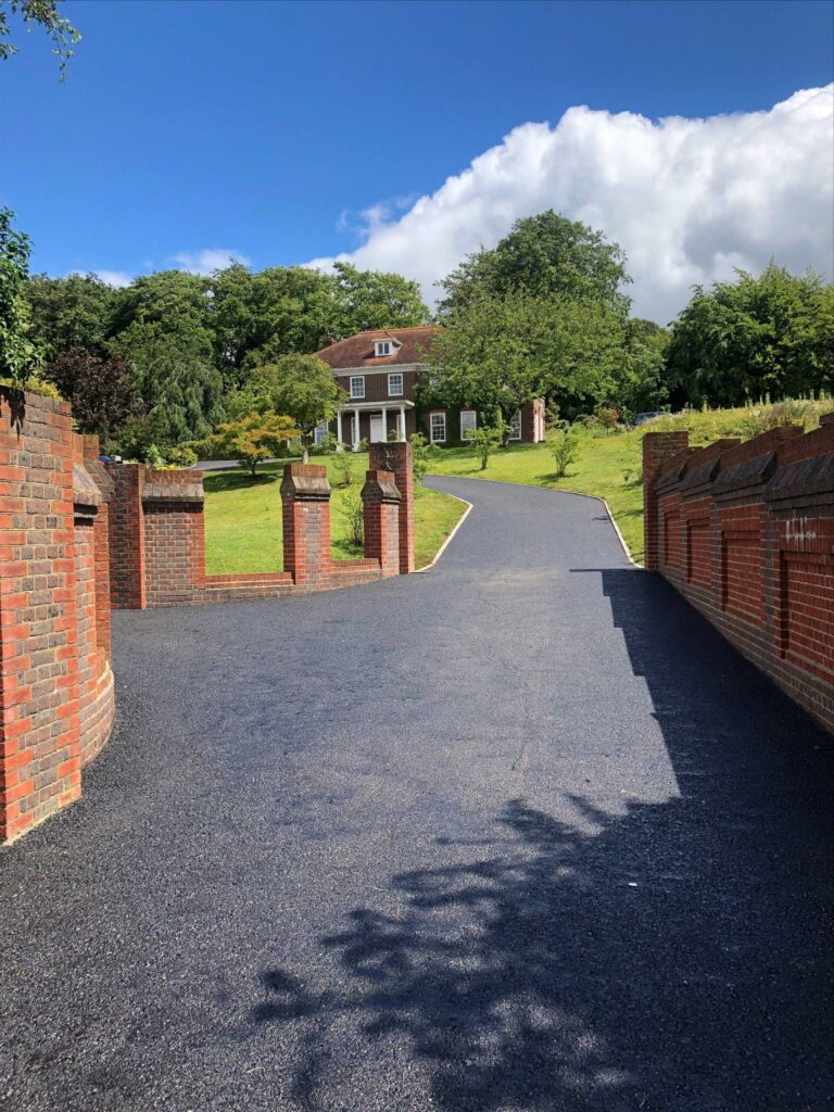 View of a newly resurfaced driveway leading up to a stately red brick home.