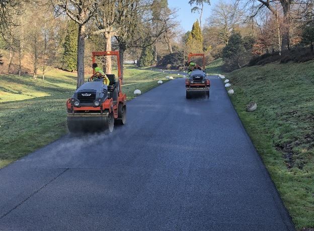Two Hazell & Jefferies team members using road rollers to lay asphalt.