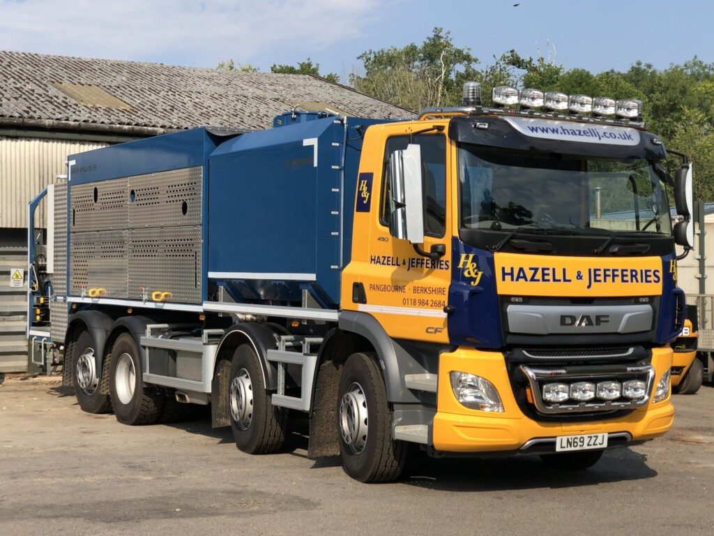 Full view of a Hazell & Jefferies lorry in yellow and navy blue.