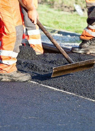 A worker in high-viz levels tarmac on a resurfaced road