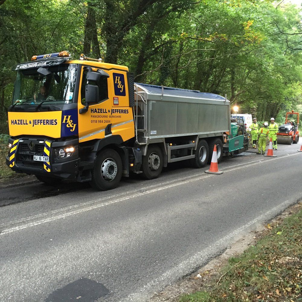 A Hazell & Jefferies tarmac lorry laying tarmac on a road, followed by workers